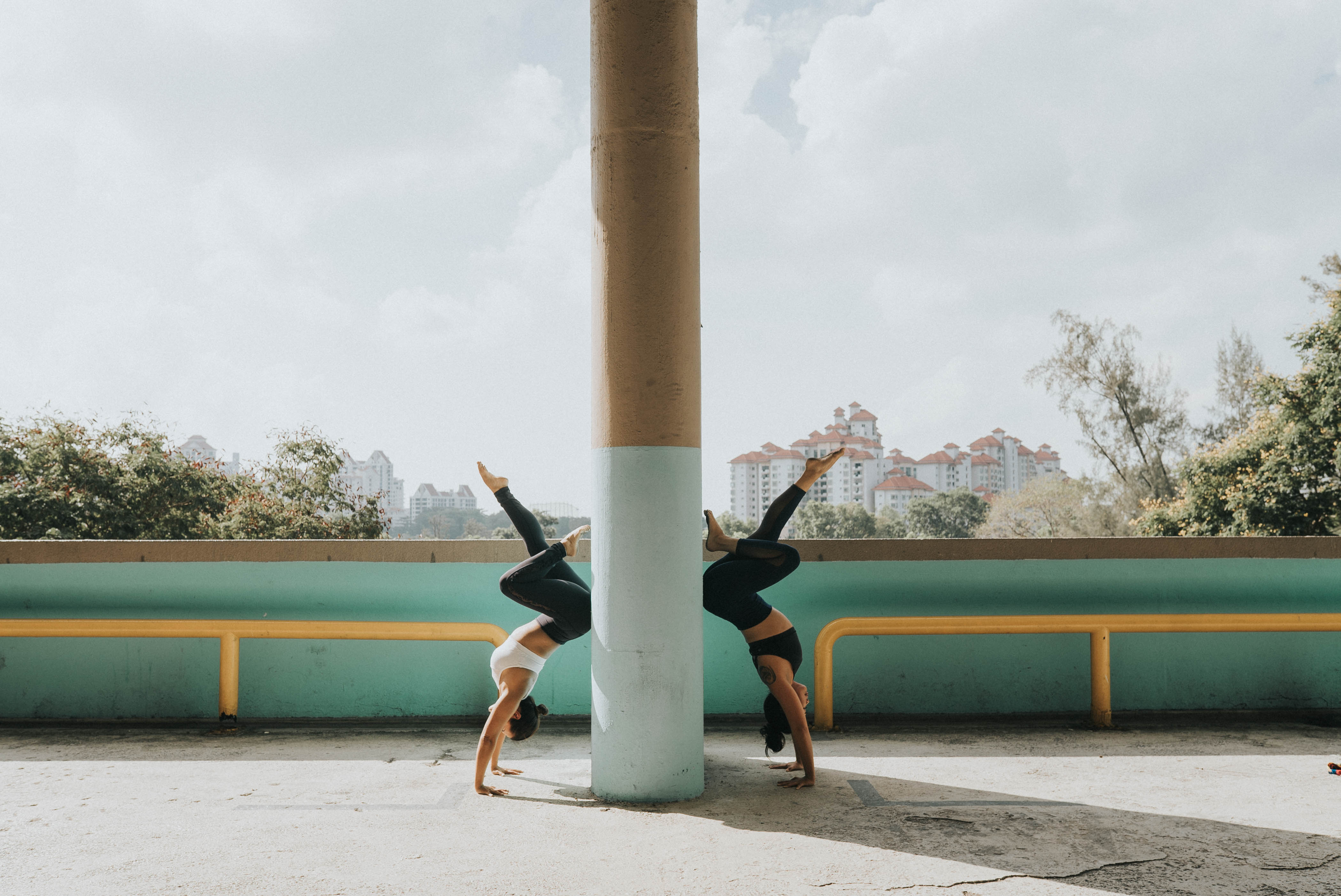 Two athletes in mirrored handstands against a pillar overlooking the city