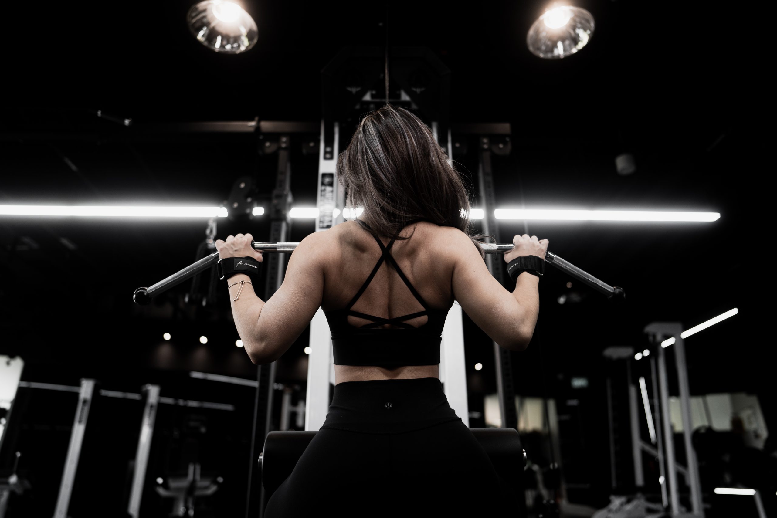 A woman training with a barbell in a dramatically lit dark gym