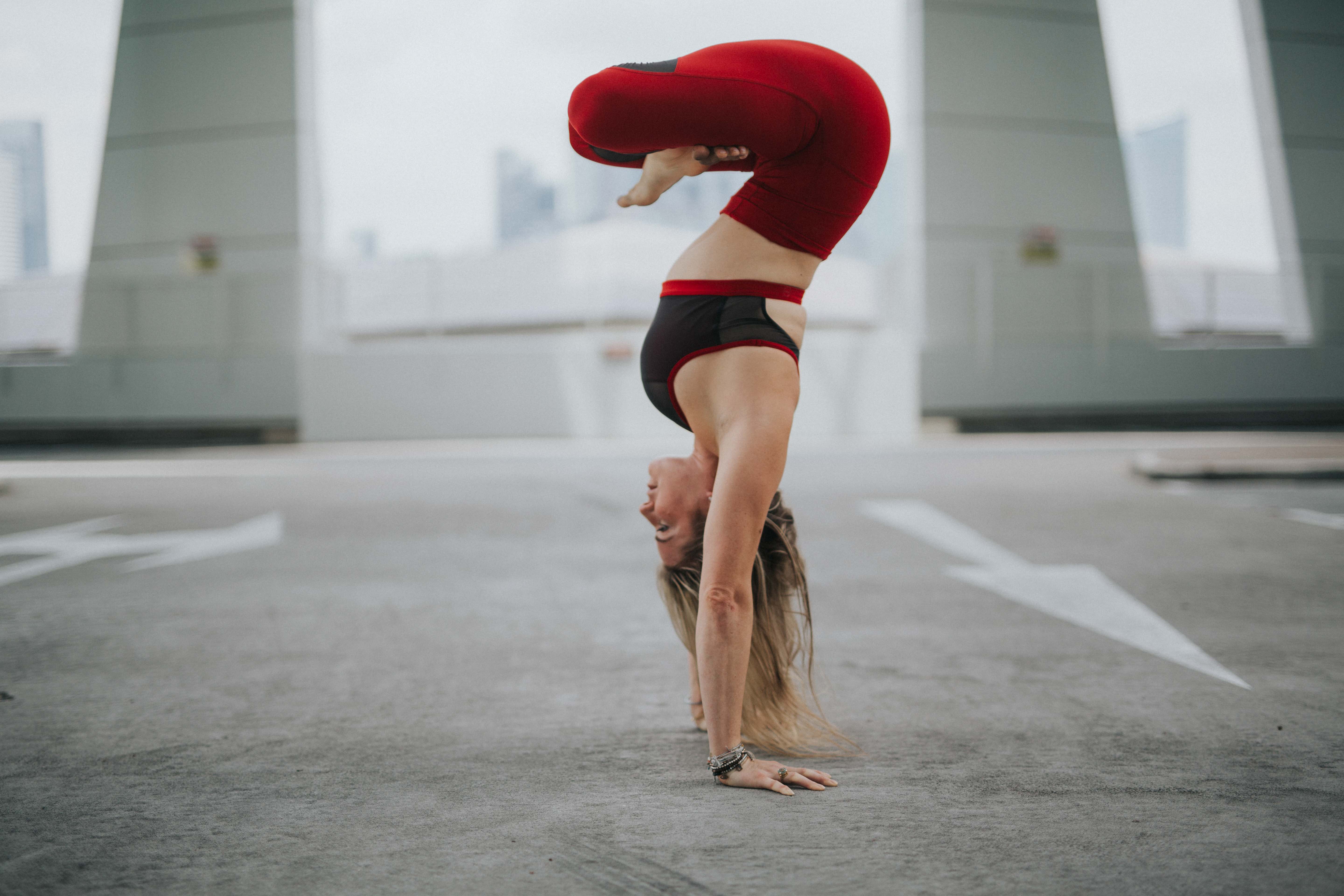 A woman in a handstand against a rooftop carpark skyline